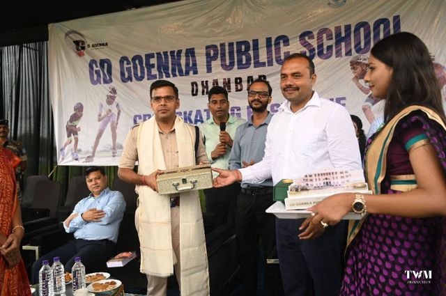 A guest receiving a memento on stage in front of the G.D. Goenka Public School banner