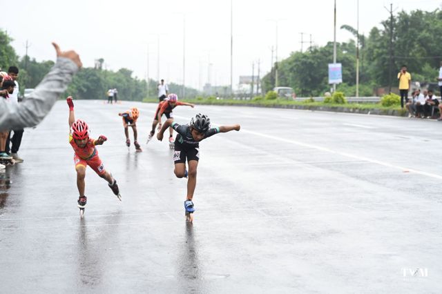 Young skaters stretching for the line at the finish of a road race on a wet road