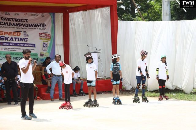 Skaters lined up at the start line while an organiser speaks into a microphone